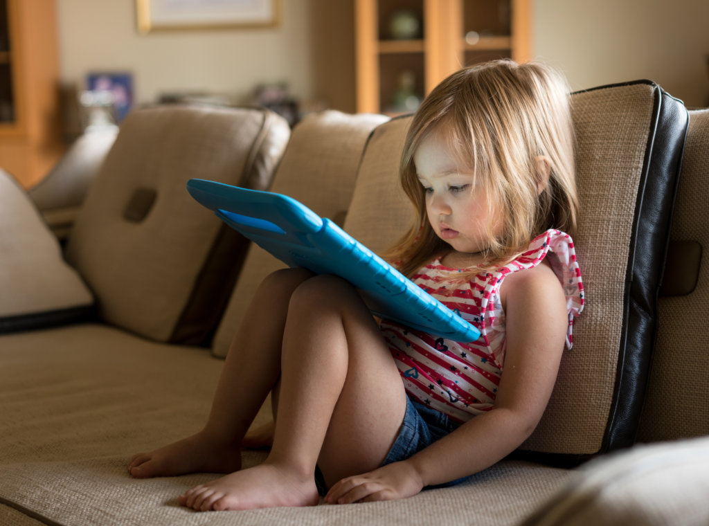 Preschool girl using a tablet computer at home